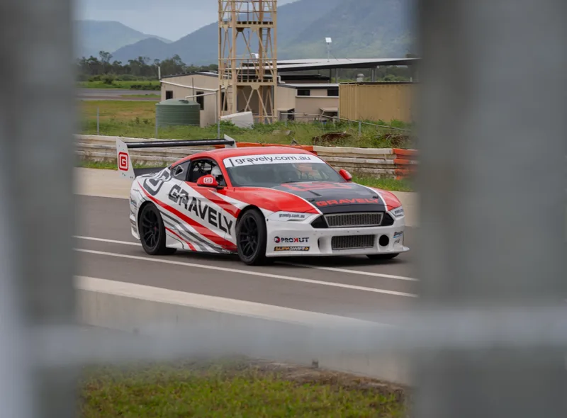 Red and white Gravely race car passing the pit area